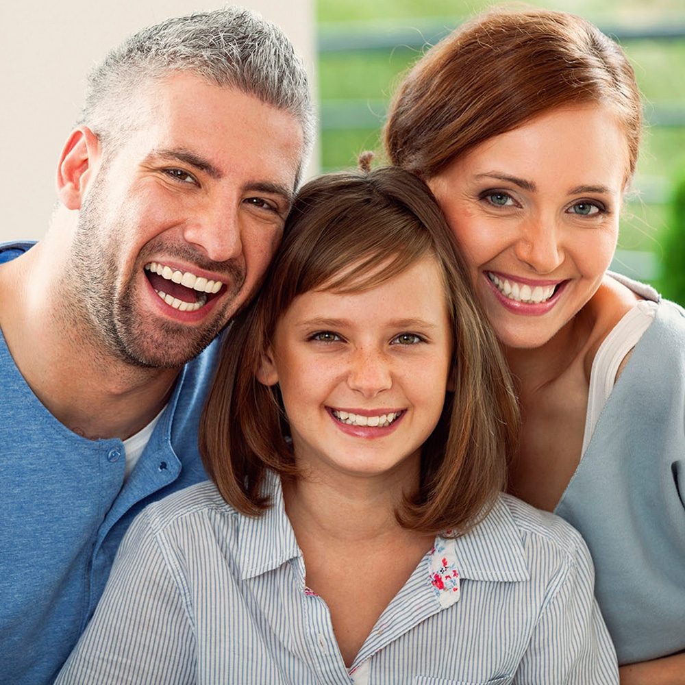A couple smiling with their child on receiving dental services from BA dentist.